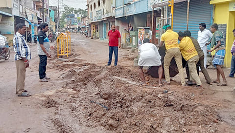 பள்ளத்ைத சீரமைக்கும் பணியில் ஈடுபட்டுள்ள ஊழியர்கள்.
