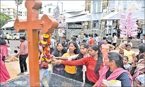 மலை மாதா ஆலயத்தில் உள்ள சிலுவையை தொட்டு பிரார்த்தனை செய்யும் பெண்கள்.