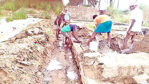 உடைப்பை சீரமைக்கும் பணியில் தொழிலாளர்கள்.