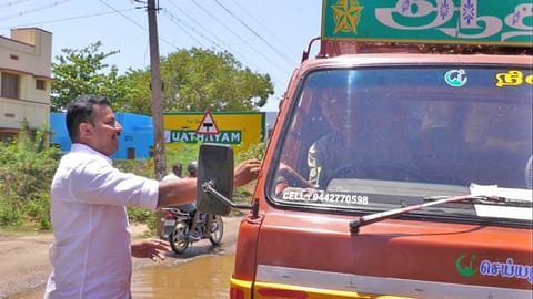 சாலைகளை சீரமைக்க கோரி வாகன ஓட்டிகளுக்கு இனிப்பு வழங்கிய அ.தி.மு.க. நிர்வாகி.