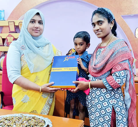 பள்ளியின் முதல்வர் சமீமா பர்வீன் குழந்தைக்கு  பாடப் புத்தகம் வழங்கினார்.
