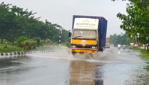 சாலையில் தேங்கிய மழை நீரில் சீறிப்பாய்ந்து செல்லும் வாகனம்.