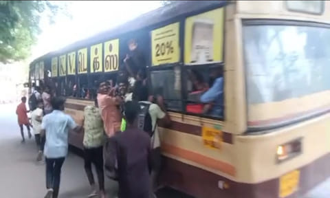 பஸ் படிக்கட்டில் தொங்கியபடி செல்லும் மாணவர்களை படத்தில் காணலாம்.