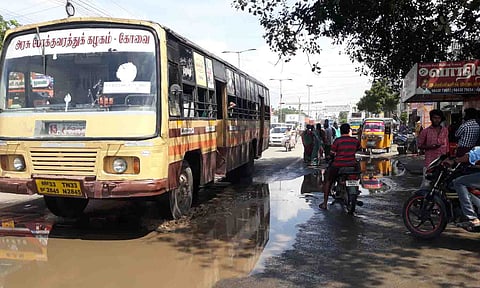பேருந்து நிறுத்தத்தில் மழைநீரும் சாக்கடை நீரும் தேங்கி நிற்கின்ற காட்சி.