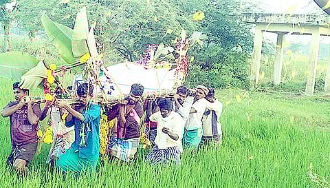 இறந்தவர் உடலை வயல்வெளியே தூக்கிச்செல்லும் கிராமமக்கள்.