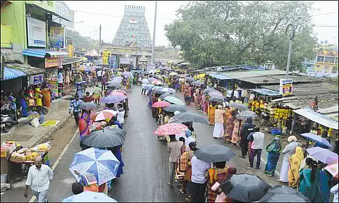 மழையில் குடையை பிடித்தபடி நீண்ட வரிசையில் காத்திருக்கும் பக்தர்களை படத்தில் காணலாம்.