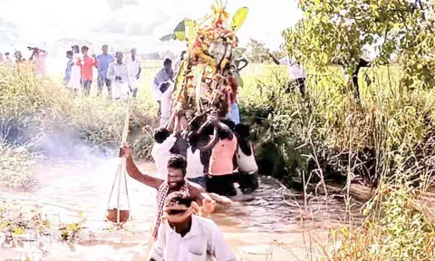 வாய்க்காலில் இறங்கி இறந்தவர் உடலை எடுத்து செல்லும் கிராமமக்கள்.