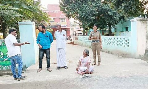 போலீஸ் நிலையம் முன்பு தரையில் அமர்ந்து தர்ணாவில் ஈடுபட்ட பெண்.