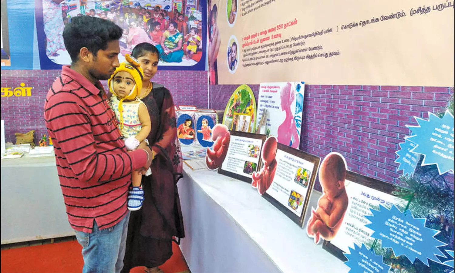 அரங்கில் ஒரு குடும்பத்தினர் ஆர்வத்துடன் பார்வையிடும் காட்சி.