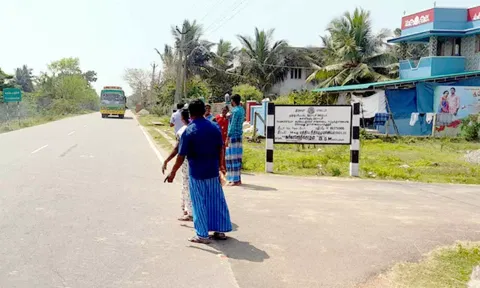 சாலையின் நடுவே பஸ்சுக்காக காத்திருக்கும் பொதுமக்கள்.