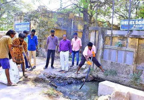சுகாதார அலுவலர் இளங்கோ முன்னிலையில் மாவட்ட கல்வி அலுவலகம் முன்பு தேங்கி கிடந்த சாக்கடை கழிவுகள் வெளியேற்றப்பட்ட காட்சி.