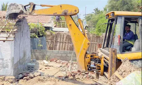 பொக்லைன் எந்திரம் மூலம் நீர் நிலை ஆக்கிரமிப்பில் இருந்த வீடுகளை அகற்றிய காட்சி.