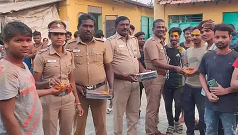 வட மாநில தொழிலாளர்களுக்கு போலீசார் இனிப்பு வழங்கிய காட்சி.