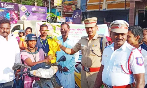 ஹெல்மெட் அணிந்து வாகனம் ஓட்டி வந்த பெண்ணுக்கு மாநகர போலீஸ் துணை கமிஷனர் சீனிவாசன் துணிப்பை, மரக்கன்றுகளை வழங்கிய காட்சி.