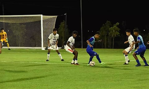 இரவில் மின்னொளி வெளிச்சத்தில் விளையாடும் இளம் கால்பந்து வீரர்கள்.