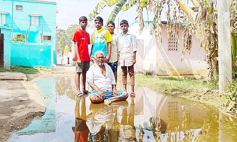 மழைநீர் அகற்ற கோரி தண்ணீரில் அமர்ந்து விவசாயி போராட்டம் நடத்தினார்.