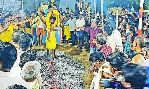 பக்தர் ஒருவர் இரு குழந்தைகளையும் சுமந்து கொண்டு தீ மிதித்தார்.