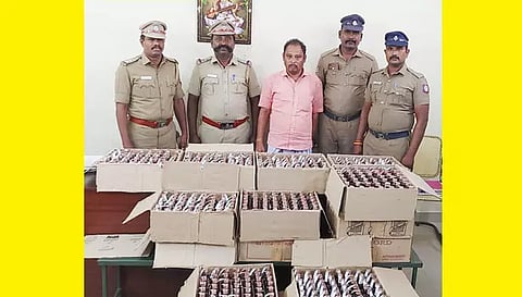 பறிமுதல் செய்யப்பட்ட மதுபாட்டில்கள் மற்றும் கைது செய்யப்பட்ட முருகனுடன் போலீசார்.