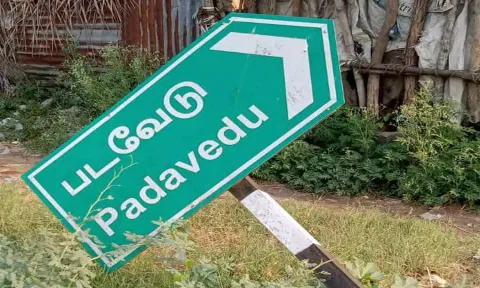 சாய்ந்த நிலையில் கிடக்கும் வழிகாட்டி பலகை