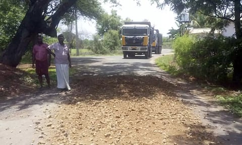 டிப்பர் லாரியில் இருந்து சாலையில் விழுந்த மண்.
