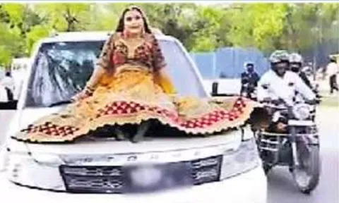 ஓடும் கார் மீது அமைந்து சென்ற இளம்பெண்ணை படத்தில் காணலாம்.