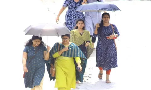பாளை முருகன்குறிச்சி- திருவனந்தபுரம் சாலையில் குடை பிடித்து செல்லும் பெண்களை படத்தில் காணலாம்.