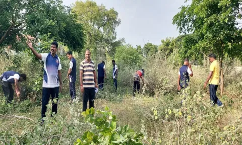விளையாட்டு மைதானத்தை தூய்மைபடுத்தும் பணியில் ஈடுபட்டுள்ள போலீசாரை படத்தில் காணலாம்.