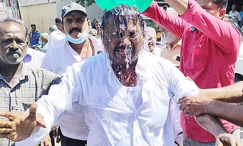 தீக்குளிக்க முயன்ற தி.மு.க. தொழிற்சங்க நிர்வாகி மீது தண்ணீரை ஊற்றும் போலீசார்.