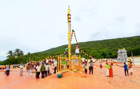 கள்ளழகர் கோவில் ஆடித்திருவிழா கொடியேற்றத்தை முன்னிட்டு கொடிமரம் வண்ண மலர்கள் கொண்ட மாலைகளால் அலங்கரிக்கப்பட்ட காட்சி.
