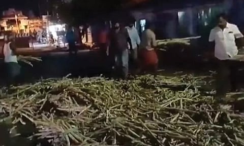 ரோட்டில் விழுந்த கிடந்த கரும்புகளை பொதுமக்கள் அகற்றிய காட்சி.