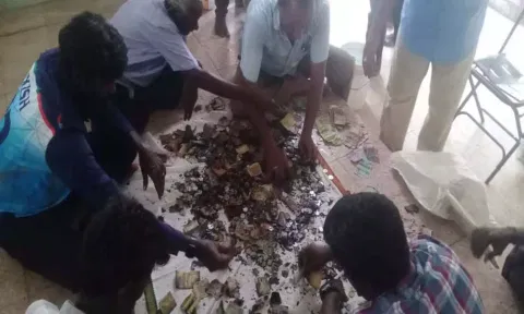 உண்டியலில் எரிந்த நிலையில் இருந்த ரூபாய் நோட்டுகளை தனியாக பிரித்தெடுப்பதை படத்தில் காணலாம்.