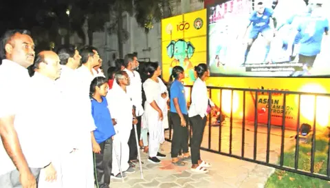 நாமக்கல் பூங்காவில் வைக்கப்பட்டுள்ள பெரிய எல்.இ.டி. திரையில் ஹாக்கி போட்டியை  ரசித்து பார்த்த பொதுமக்கள்.
