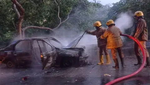 காரில் பற்றிய தீயை தீயணைப்பு துறையினர் அணைத்த காட்சி.