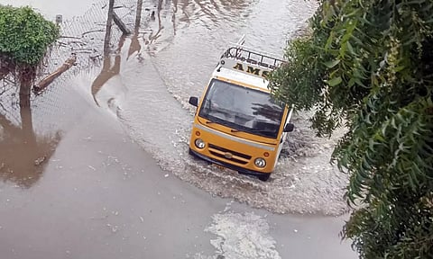 தேங்கி நிற்கும் மழைநீரில் ஊர்ந்து செல்லும் வாகனத்தின் காட்சி.