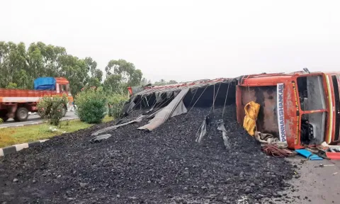 சாலையின் நடுவே கவிழ்ந்த லாரியை படத்தில் காணலாம்.