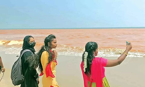 செம்மண் நிறத்தில் மாறிய கடல் நீரை சுற்றுலா பயணிகள் ஆர்வத்துடன் செல்போனில் படம் பிடித்த காட்சி.