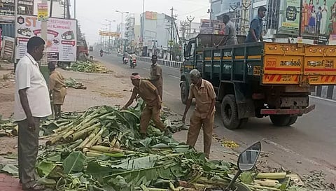 சாலையோரம் உள்ள குப்பைகளை அகற்றும் பணியில் ஈடுபட்டுள்ள நகராட்சி பணியாளர்கள்.