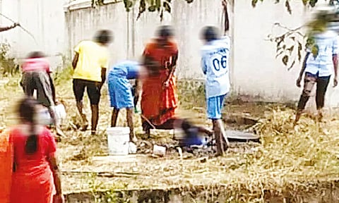 பள்ளியில் உள்ள கழிவறை தொட்டியை மாணவர்களை கொண்டு சுத்தம் செய்ய வைத்த காட்சி.