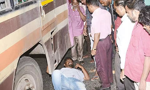 திருப்பூரில் பஸ் சக்கரம் முன்பு படுத்து வாலிபர் போராட்டம்