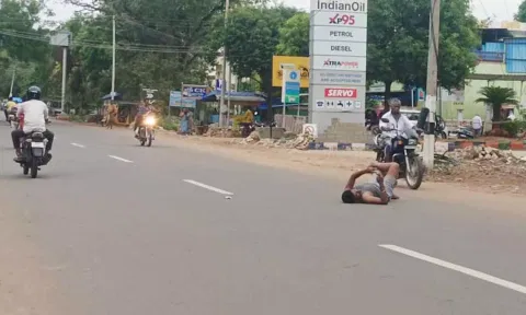 நடுரோட்டில் கால்மேல் கால்போட்டு படுத்து செல்போன் பார்த்த வாலிபர்