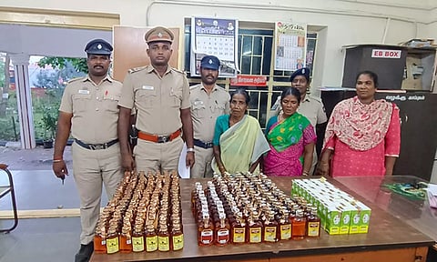 கைது செய்யப்பட்ட பெண்களையும், அவர்களை பிடித்த போலீசாரையும், பறிமுதல் செய்யப்பட்ட மதுபாட்டில்களையும் காணலாம்.