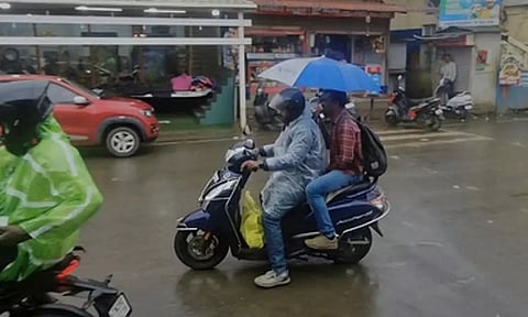 ஊட்டியில் பெய்த கனமழை காரணமாக அங்குள்ள பொதுமக்கள் குடையுடன் வாகனங்களில் பயணித்த காட்சி.