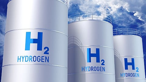 Close-up of three cylindrical storage tanks with the blue text "H2 HYDROGEN" on them, representing an industrial green hydrogen storage facility.