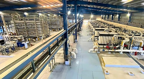 An interior view of a large-scale industrial water treatment facility showing rows of white horizontal Reverse Osmosis membrane pressure vessels and intricate piping systems housed within a blue steel-framed warehouse.