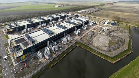 Aerial view of a sprawling data center facility built directly alongside a drainage canal.