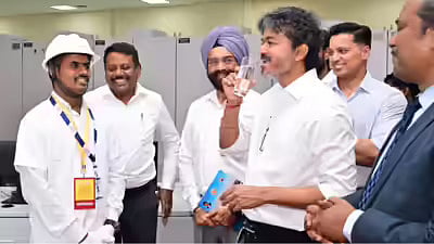 Tamil Nadu CM Joseph Vijay drinking a glass of water inside a control room during a site inspection of a desalination plant, with engineers and staff in hard hats watching and smiling in the background