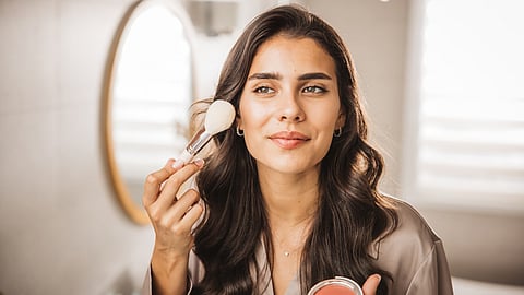A beautiful women applying blush.