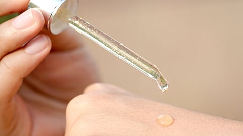 Drop of serum being dropped on a palm.