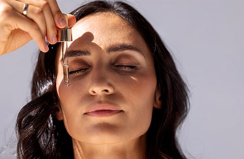 Women applying peprides on her face.