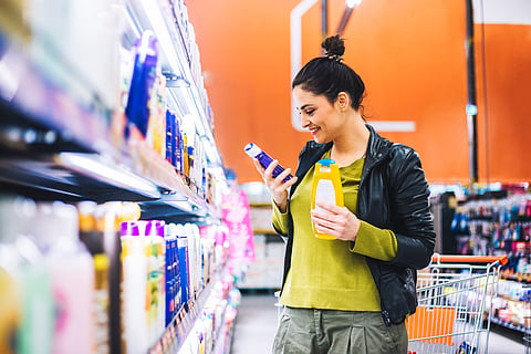 Women in shampooo aisle selecting haircare products.